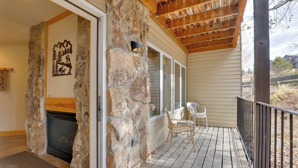 A stone fireplace, a wooden deck, and a covered porch with a railing. - 1/2 Mi to Granby Ranch: Townhome w/ Fireplace! (Granby)
