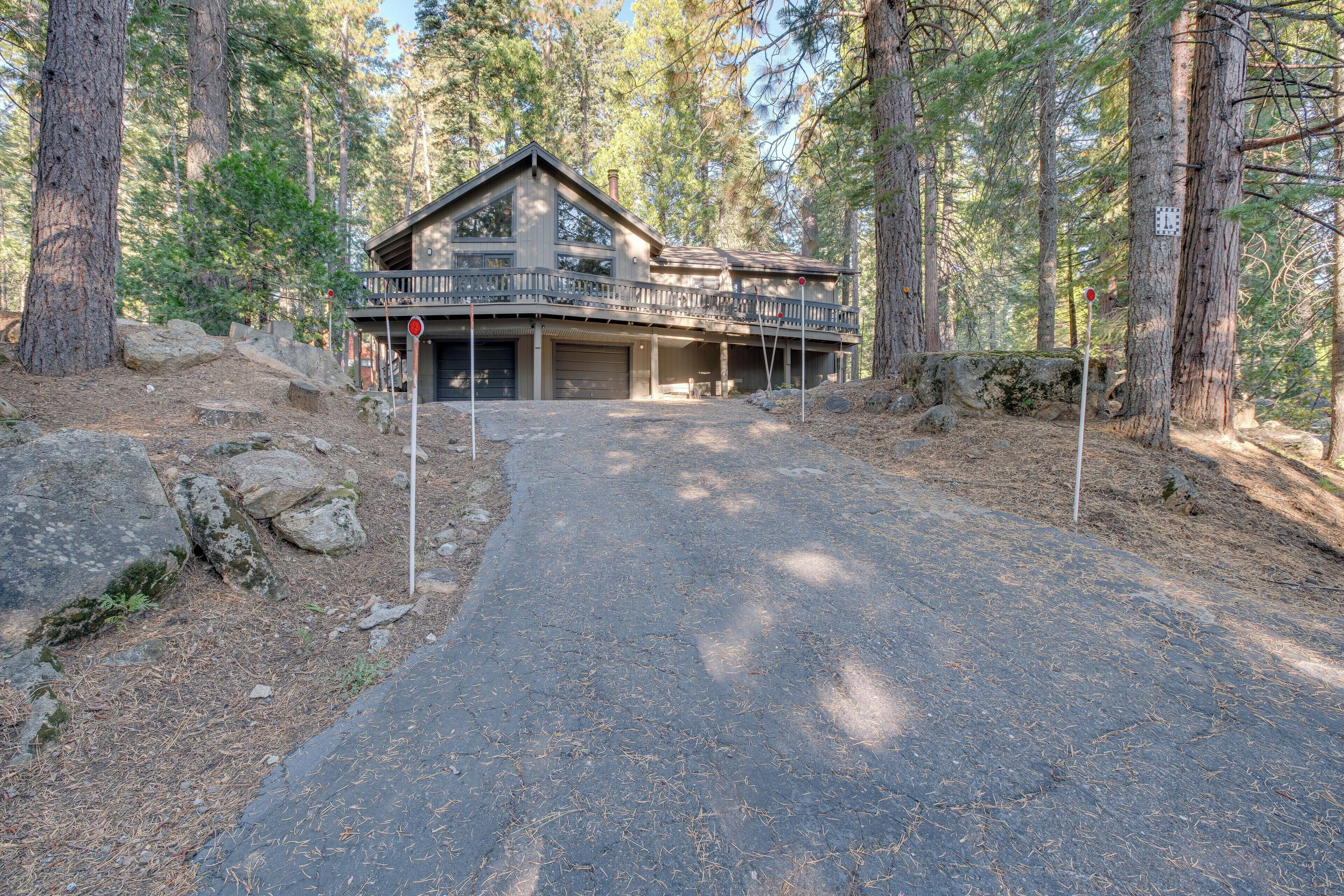 A two-story cabin with a balcony, surrounded by tall pine trees.