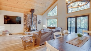 Ein geräumiges Wohnzimmer mit Holzboden, einem Kamin, einem großen Sofa und einem Essbereich mit Tisch und Stühlen.