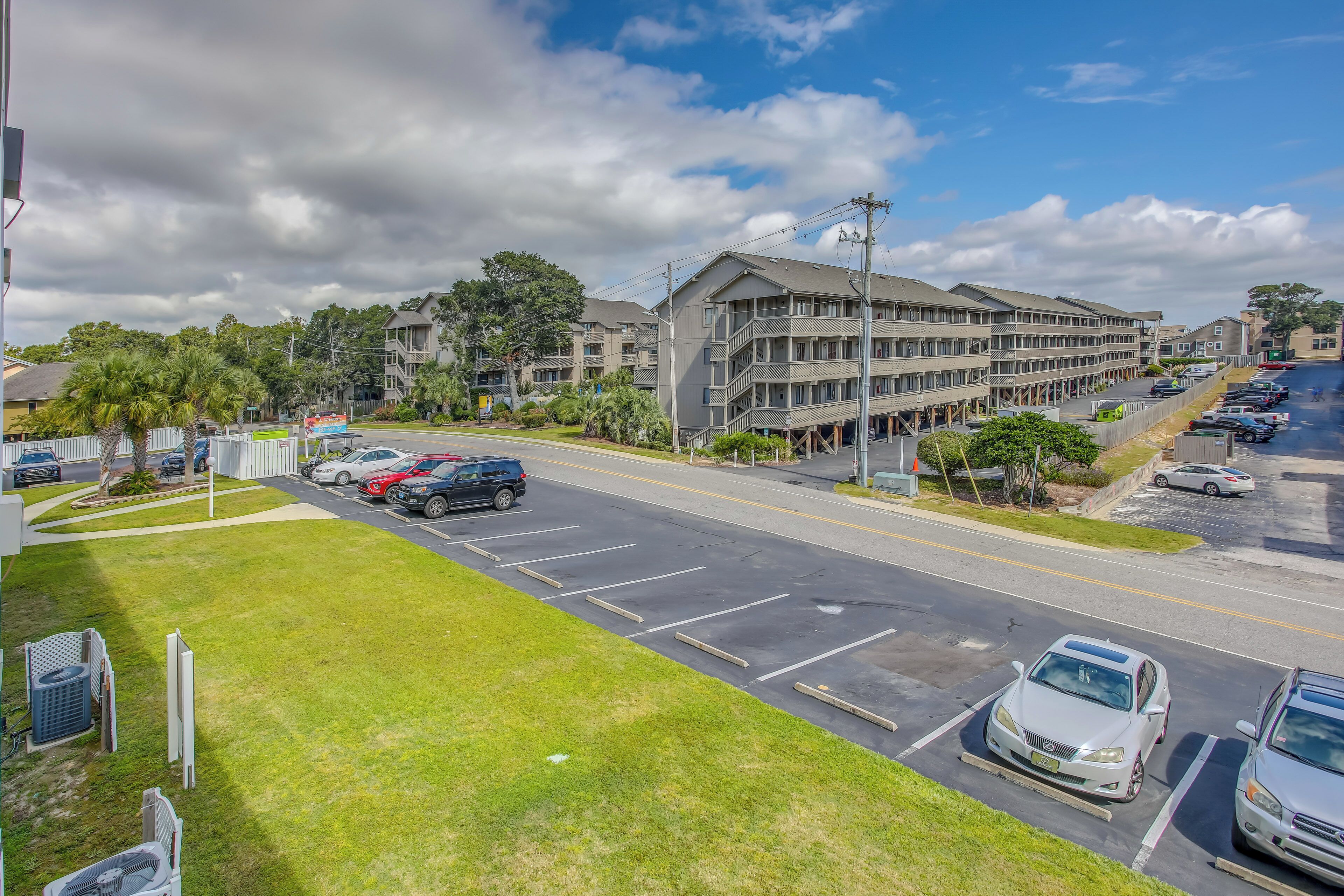 A multi-story hotel with a parking lot and a grassy area in front.