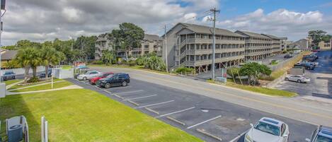 A multi-story hotel with a parking lot and a grassy area in front.