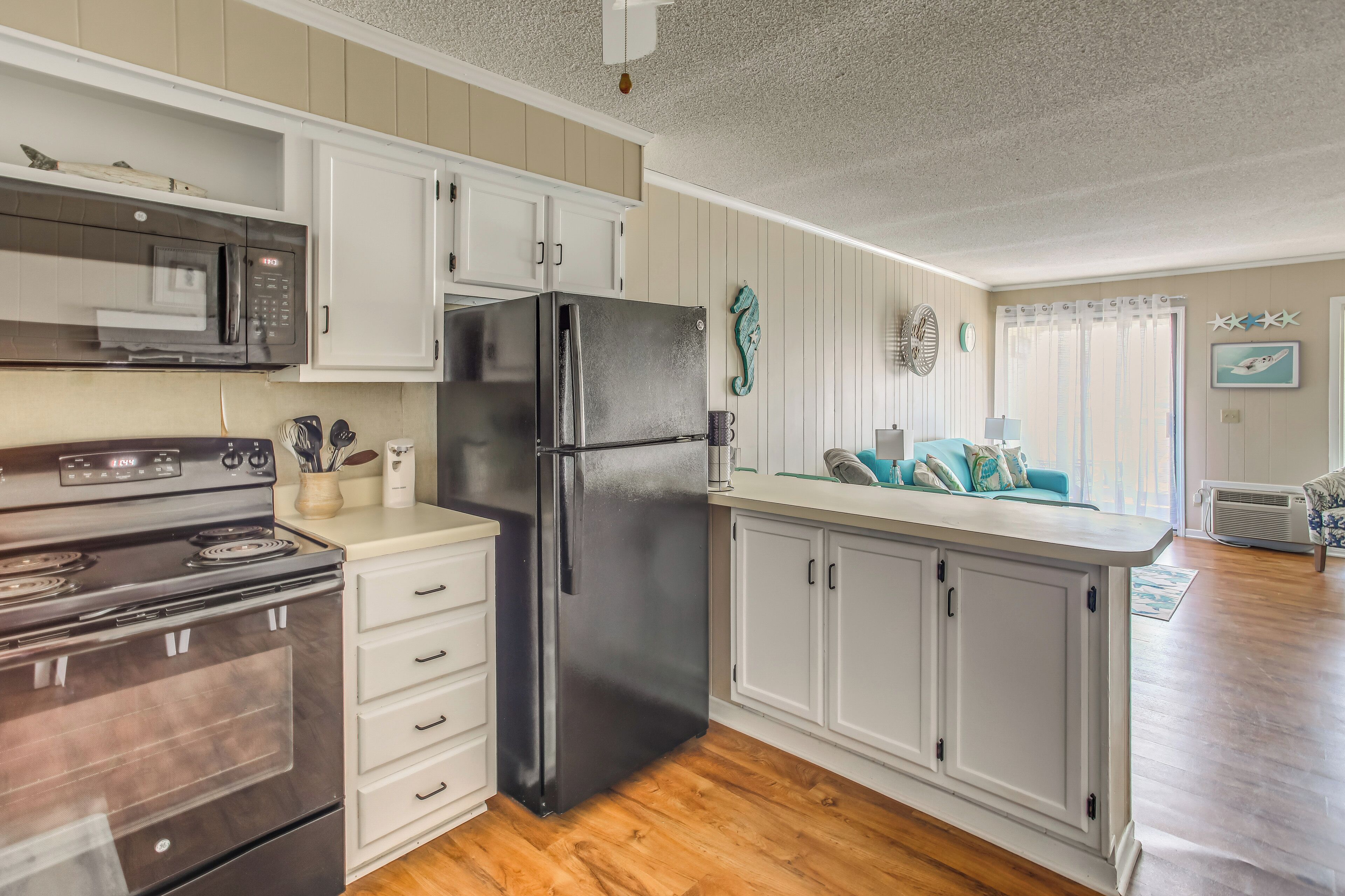 A kitchen with white cabinets, a stainless steel refrigerator, a microwave, and a stove.