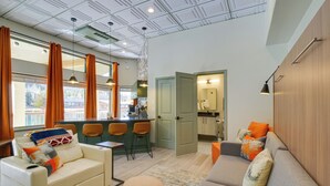 Un salon moderne comprenant un canapé, une table basse et un coin repas avec des chaises.