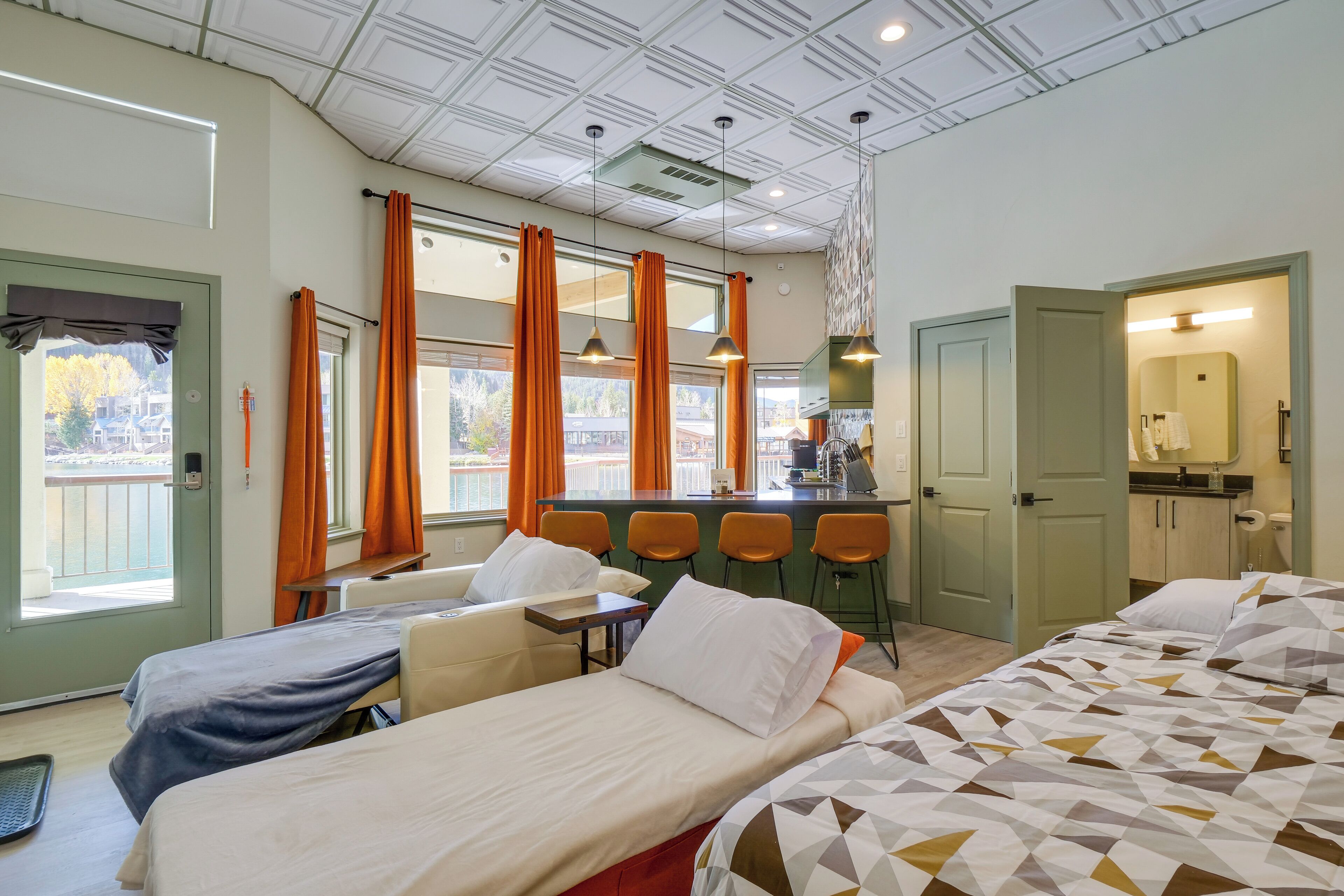 Habitación de hotel con dos camas, kitchenette, zona de bar y baño.
