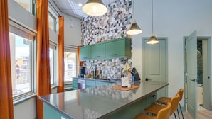 Une cuisine moderne dotée d’un îlot central, de tabourets de bar et d’un crédence décorée.