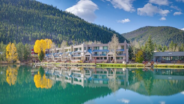Un hôtel composé de plusieurs bâtiments situés le long d’un lac, entouré de collines boisées.