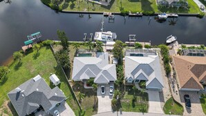 A residential area with houses, a dock, and a boat. - Pet-friendly Waterfront Home w/ Pool! (Port Charlotte)