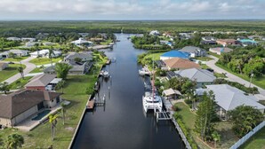 A residential area with houses, a canal, and a boat docked at a pier. - Pet-friendly Waterfront Home w/ Pool! (Port Charlotte)