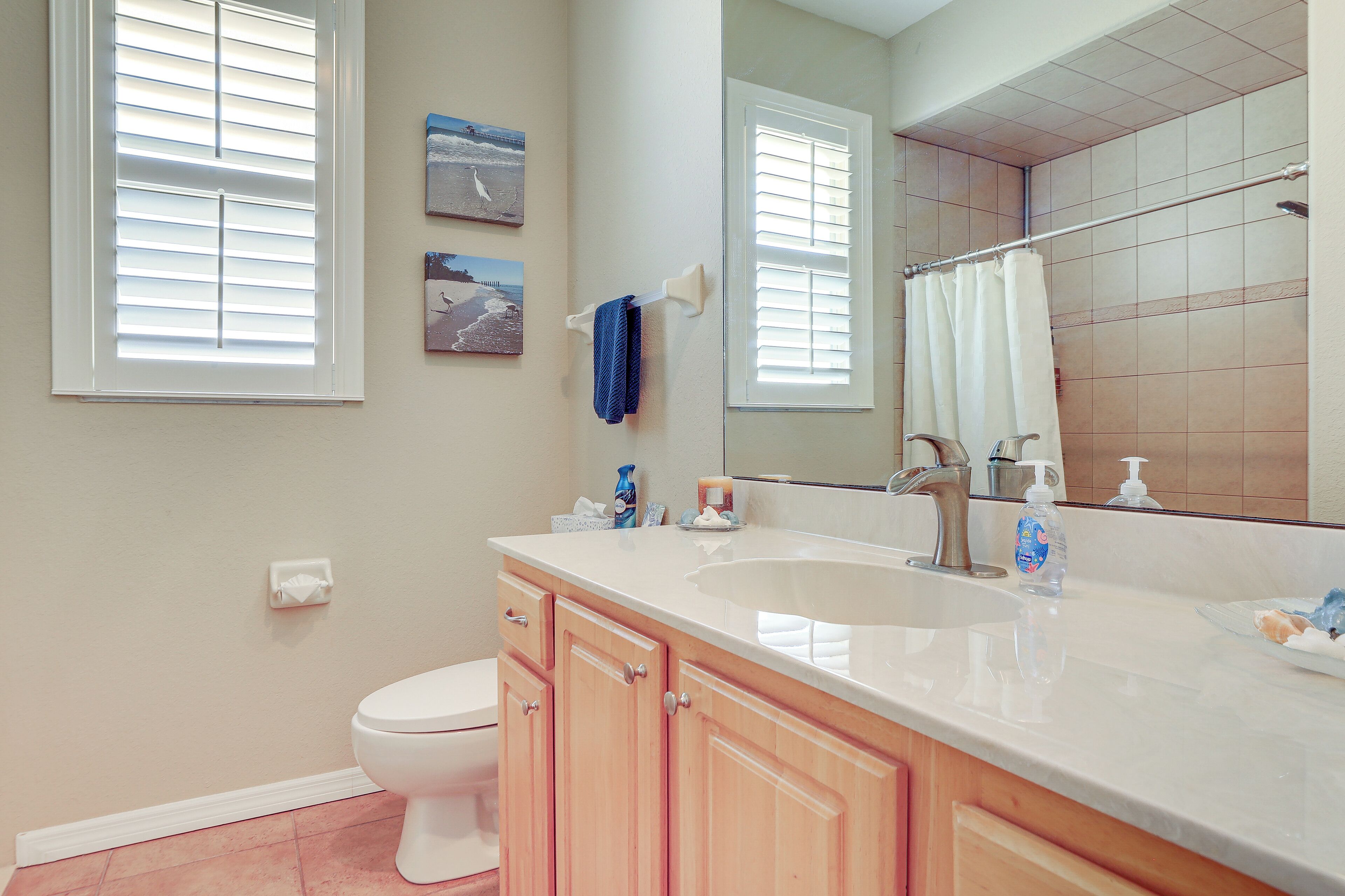 A bathroom with a white sink, wooden vanity, a toilet, and a large mirror.