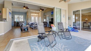 A spacious living area with a large glass door leading to a balcony, a ceiling fan, and a dining area with a table and chairs. - Pet-friendly Waterfront Home w/ Pool! (Port Charlotte)