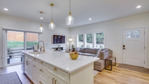 A modern kitchen with a large island, pendant lights, and a view to the outdoors. - Private Yard & Fire Pit! Modern Kirkland Abode (Kirkland)