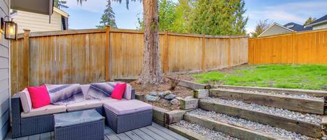 A deck with outdoor furniture, a wooden fence, and a landscaped garden area.