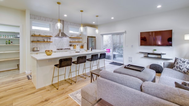 A modern kitchen with a central island, bar stools, and pendant lighting. - Private Yard & Fire Pit! Modern Kirkland Abode (Kirkland)