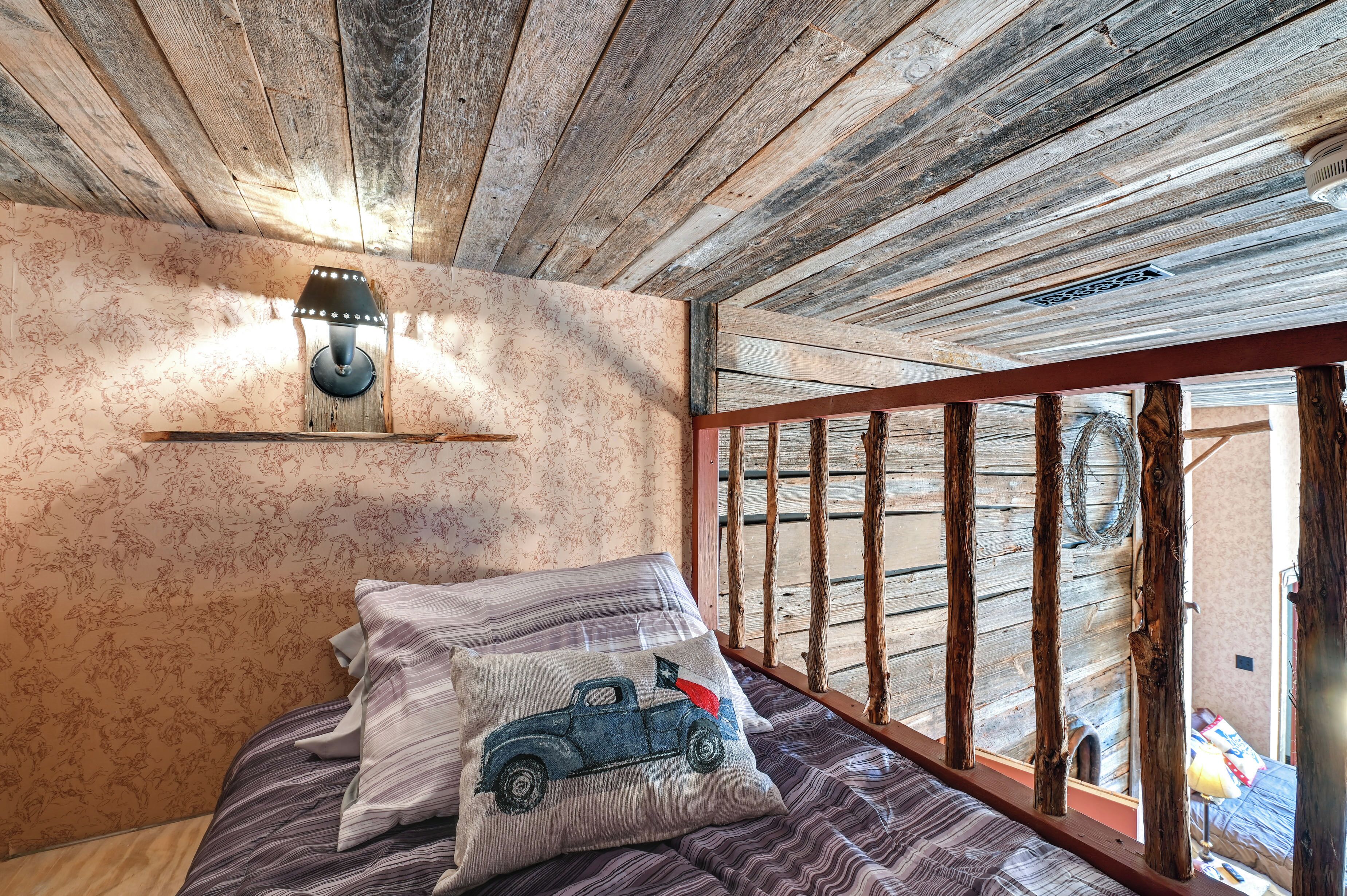 Une chambre rustique avec des poutres apparentes, un lit avec une literie à rayures et une lampe fixée au mur.