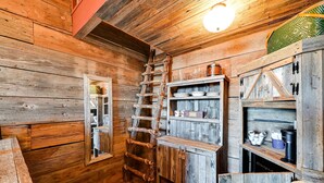 L'interno accogliente di una baita in legno, con una scala di legno, mensole piene di utensili da cucina e uno specchio.
