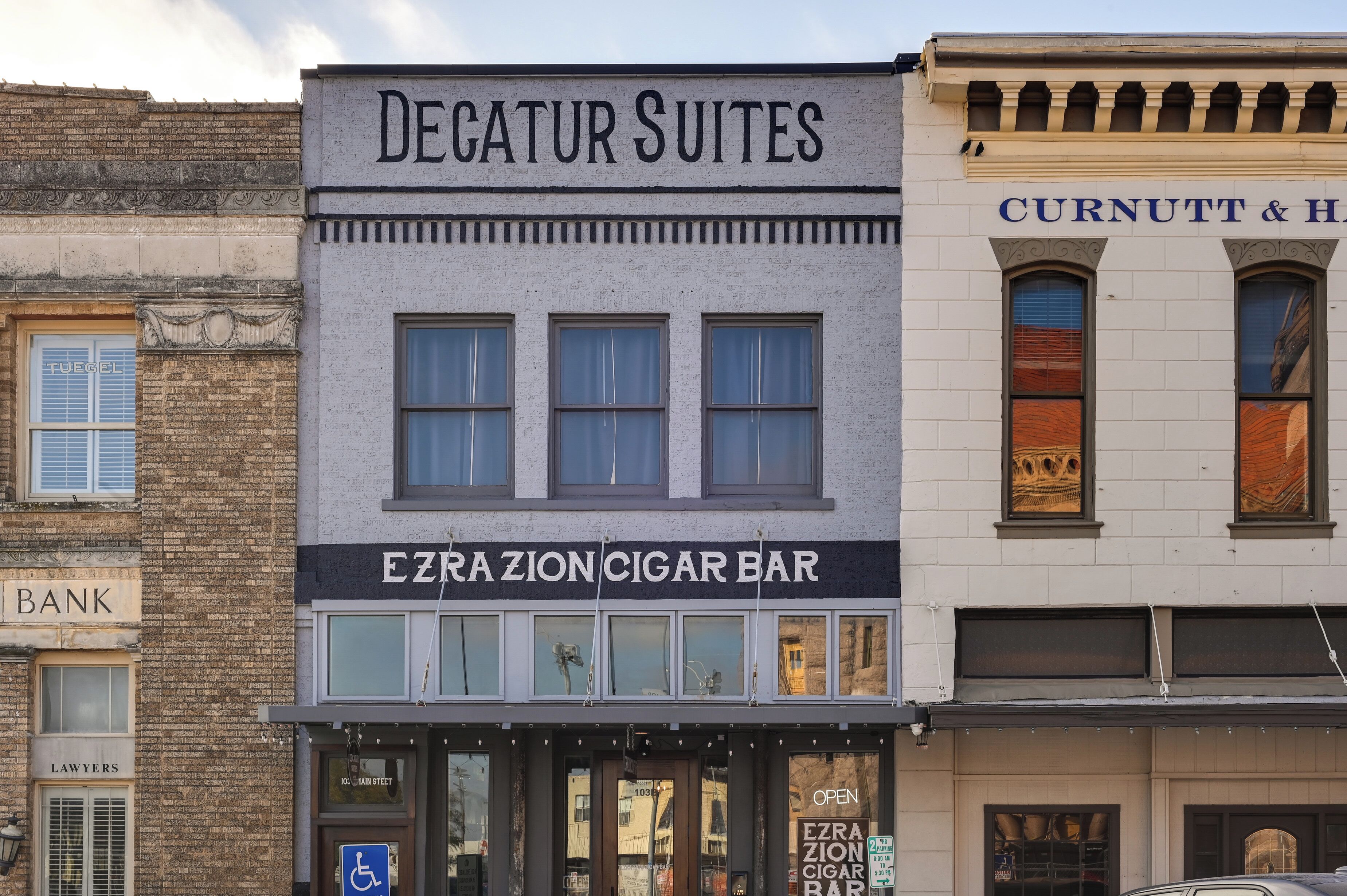 A building with a sign for 'Degatur Suites' and 'Ezra Zion Cigar Bar' on the ground floor.