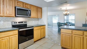 A modern kitchen with wooden cabinets, a stainless steel microwave, a double oven, and a granite countertop. - Pet-friendly Englewood Home - 4 Mi to Beach! (Englewood)