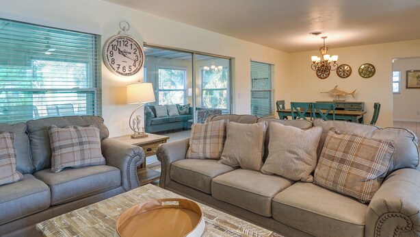 A living room with a sofa, coffee table, and a dining area with chairs and a table. - Pet-friendly Englewood Home - 4 Mi to Beach! (Englewood)