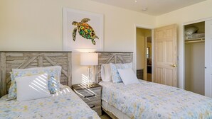 A bedroom with two beds, a wooden headboard, a nightstand with a lamp, and a framed picture of a sea turtle on the wall. - Pet-friendly Englewood Home - 4 Mi to Beach! (Englewood)