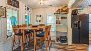 A dining area with a wooden table and chairs, a black refrigerator, and a bookshelf with board games. - Lakefront Antioch Cottage w/ Dock & Gas Grill! (Antioch)