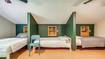 A dormitory room with two single beds, a chair, and built-in shelves.