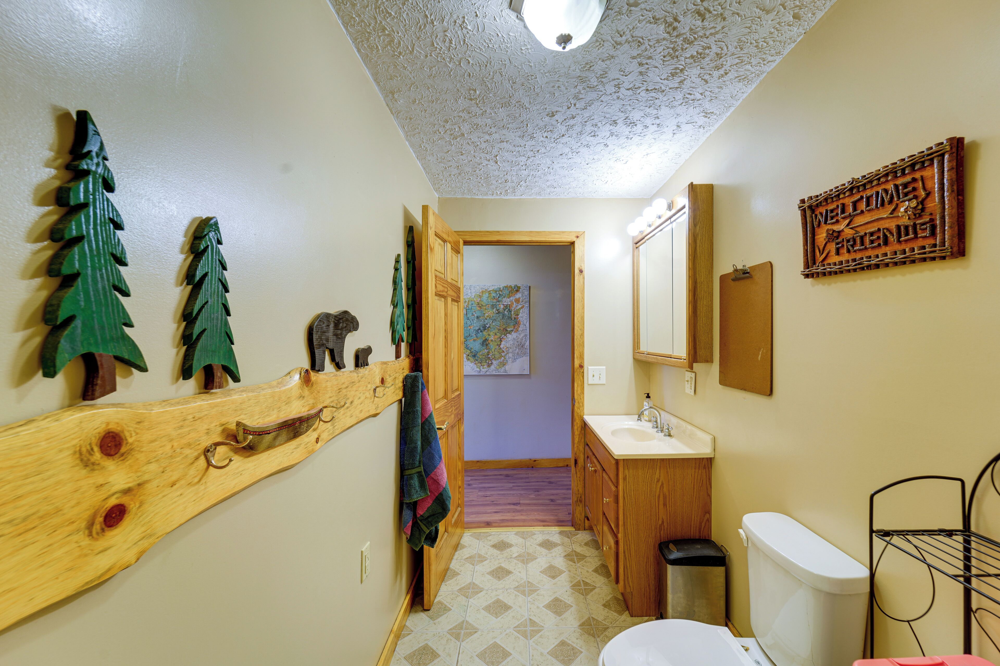 Une salle de bain avec un meuble-lavabo en bois, des toilettes et un lavabo. On y trouve également un porte-serviettes et un miroir au mur.