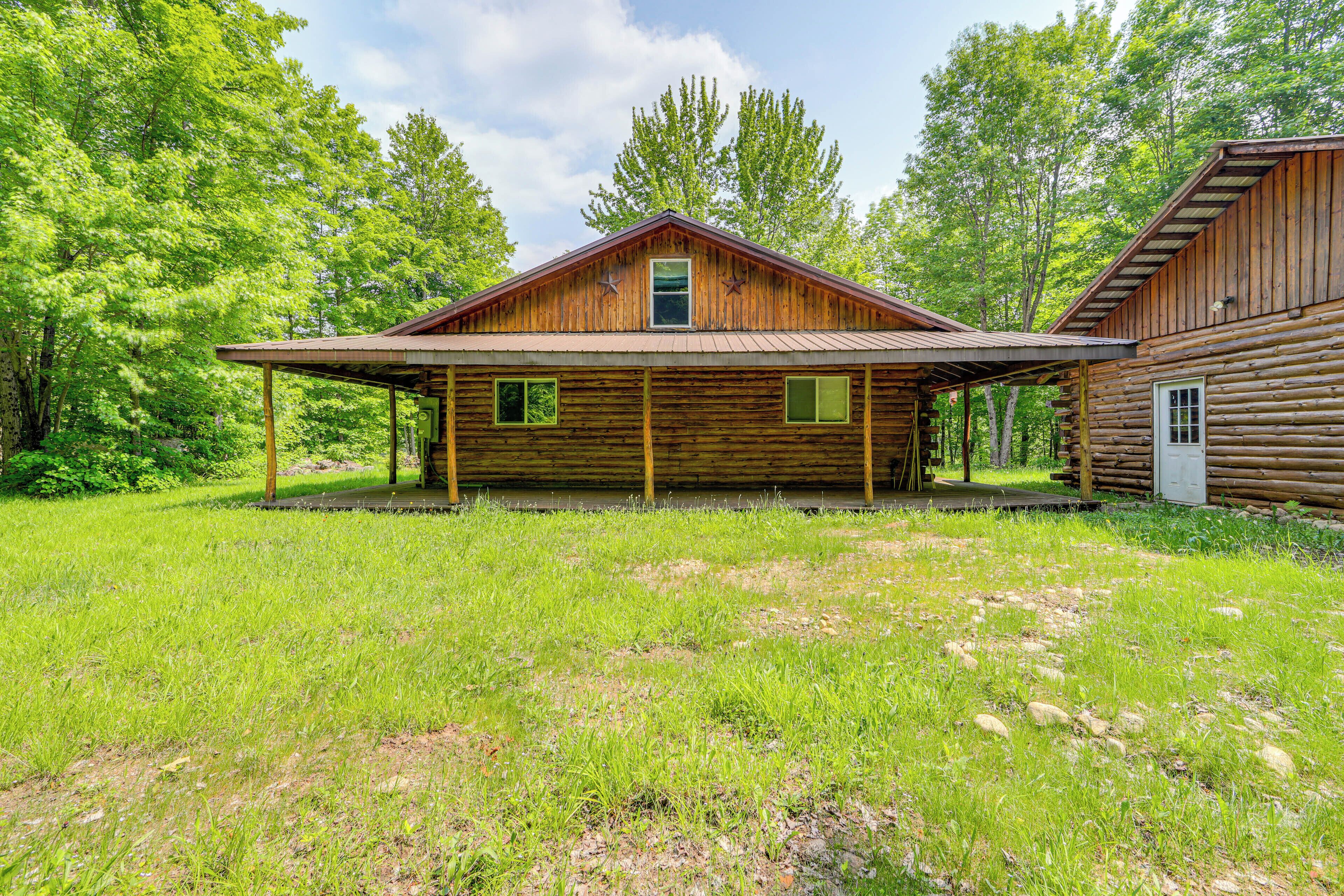 A rustic log cabin with a covered porch and a small attached shed.
