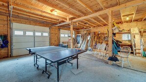 Amplio espacio interior con mesa de ping pong, paredes de madera y un garaje con varias puertas.