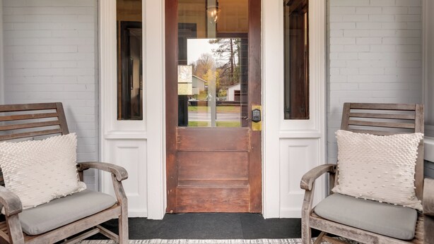 A wooden door with a glass panel, flanked by two wooden chairs with cushions. - Spacious Home in Ramsay: 9 Smart TVs + Pool Table! (Ramsay)