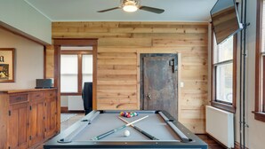 A pool table with balls and cues, wooden cabinets, a ceiling fan, and a door with a window. - Spacious Home in Ramsay: 9 Smart TVs + Pool Table! (Ramsay)
