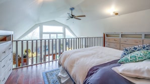 Une chambre à coucher avec un lit, une commode, un ventilateur de plafond et une fenêtre.