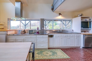 A modern kitchen with white cabinets, a stainless steel range hood, a large window, and a view of the outdoors. - Pet-friendly Pilot Studio w/ Vineyard Views! (Pilot)