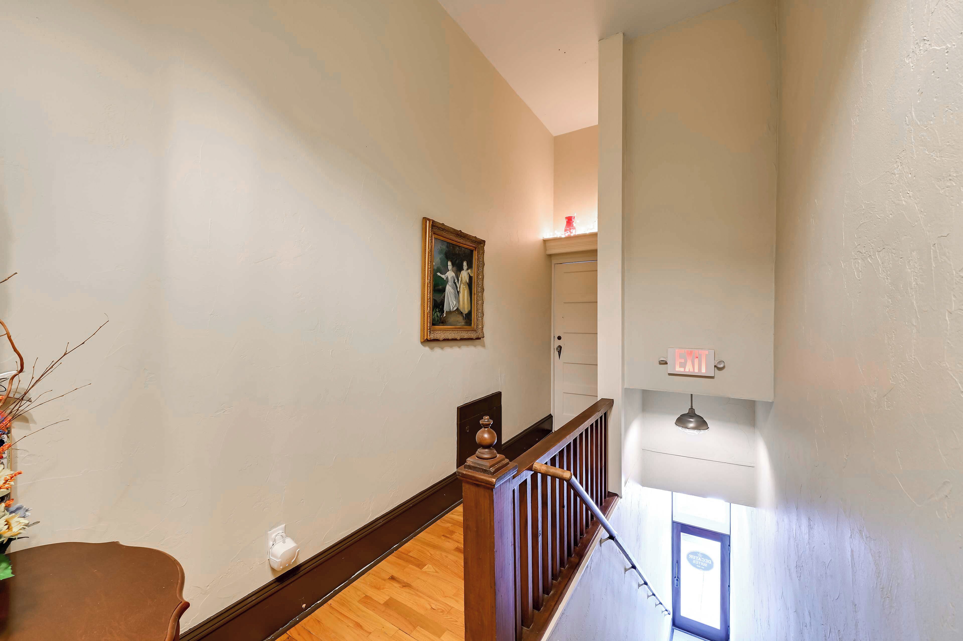 A staircase with a wooden handrail and a white wall with a framed picture.
