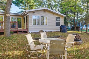 A small house with a porch, a fire pit, and outdoor seating. - Lakefront Nekoosa Home: Private Beach & Boat Dock! (Nekoosa)