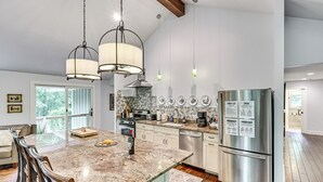 A modern kitchen with a granite countertop, stainless steel appliances, and pendant lighting.