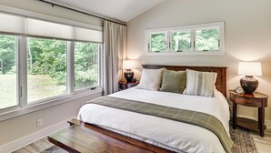 A bedroom with a large bed, two bedside tables with lamps, a window with blinds, and a ceiling fan.