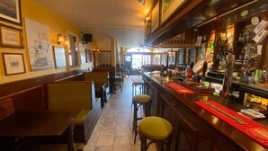 A bar area with wooden booths, a counter with bar stools, and various bottles and glasses. - The Lady Hamilton B&B (Portsmouth)