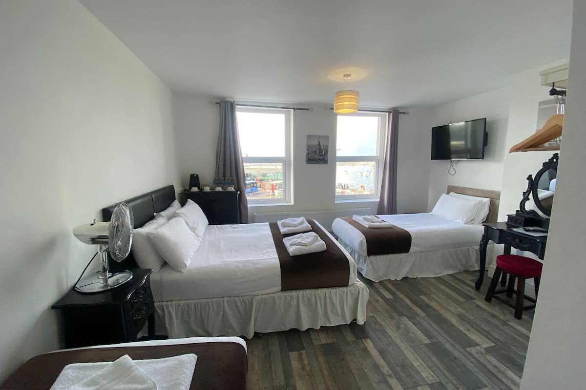 Een hotelkamer met twee bedden, een bureau, een televisie en uitzicht op de stad.