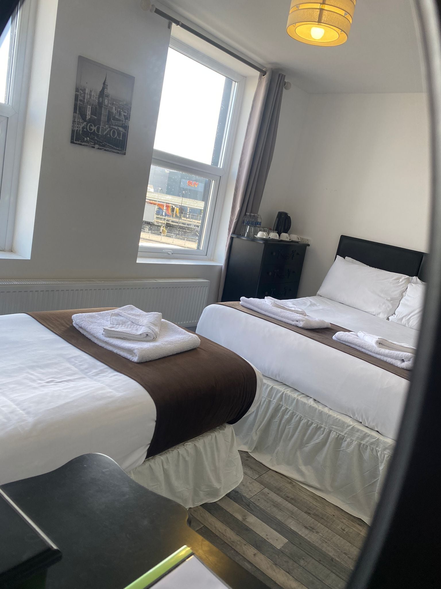 A hotel room with two beds, a view of a cityscape, and a window with curtains.