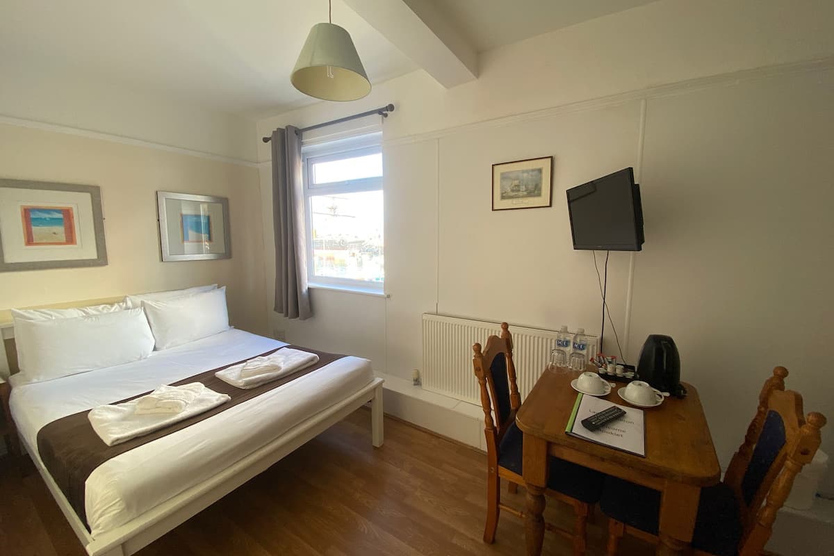 Een hotelkamer met een bed, een tafel met een stoel, een televisie en een raam met gordijnen.