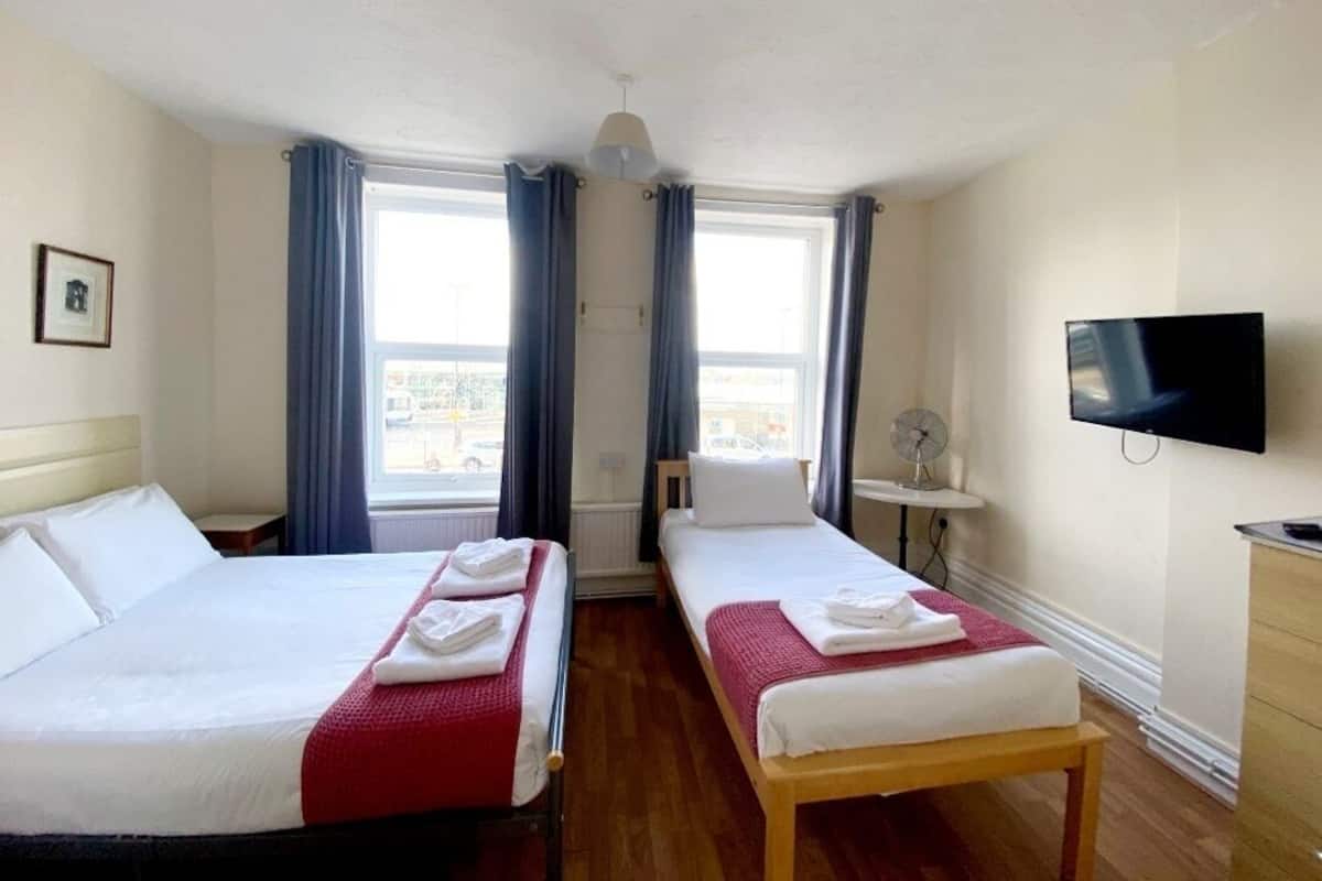 Een hotelkamer met twee bedden, een televisie en een raam met gordijnen.