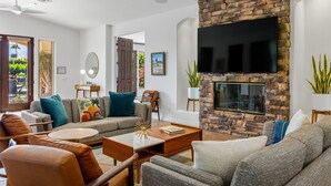A modern living room with a stone fireplace, a flat-screen TV, and comfortable seating. - Mirador Desert Oasis – Mediterranean Escape (Palm Springs)