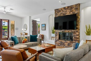 A modern living room with a stone fireplace, a flat-screen TV, and comfortable seating.