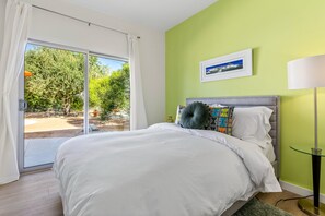 A bedroom with a bed, a window with curtains, a green wall, and a picture frame. - Stargazer - Vibrant Mid-Century Retreat (Palm Springs)