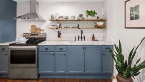 A modern kitchen with blue cabinets, stainless steel appliances, and a marble countertop. - 2BR Stowe Mountain Unit | River & Ski Access (Stowe)