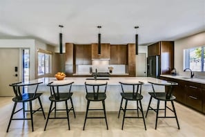 A modern kitchen with a central island, bar stools, and stainless steel appliances. - Deluxe Desert Getaway | Heated Pool & Hot Tub (Scottsdale)