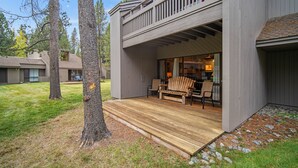 Une maison moderne dotée d’une terrasse en bois, d’un balcon et d’un patio aménagé avec du mobilier d’extérieur.