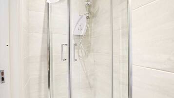 Ducha envuelta en vidrio con cabezal de ducha de mano y panel de control.