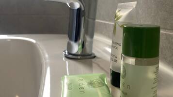 A bathroom sink with a chrome faucet, a green bottle of shampoo, and a green soap bar.