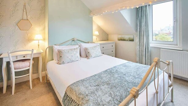 A bedroom with a bed, a desk, a chair, and a window with curtains. - Host & Stay | Allium House (Whitby)